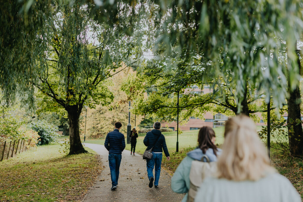People walking on a leafy path on campus